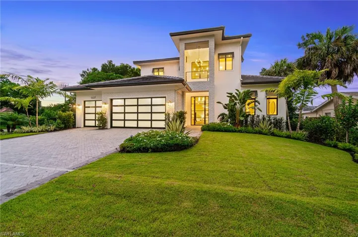 View of front facade featuring a garage and a lawn