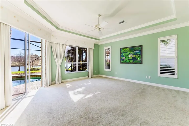 Carpeted empty room featuring crown molding, a sunroom, a water view, and ceiling fan