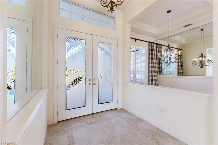 Entryway with french doors, a chandelier, inlaid floor details, tile patterned flooring, and ornamental molding