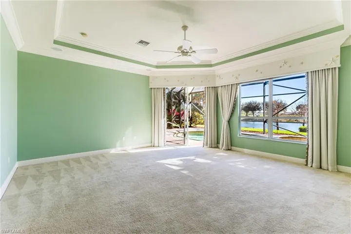 Unfurnished room with carpet flooring, crown molding, a water view, ceiling fan, and a raised ceiling