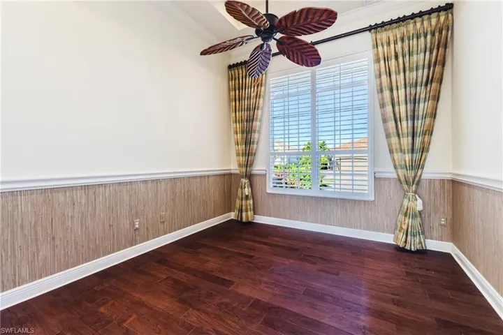 featuring wainscoting, dark wood-style flooring, crown molding, wood walls, and a ceiling fan