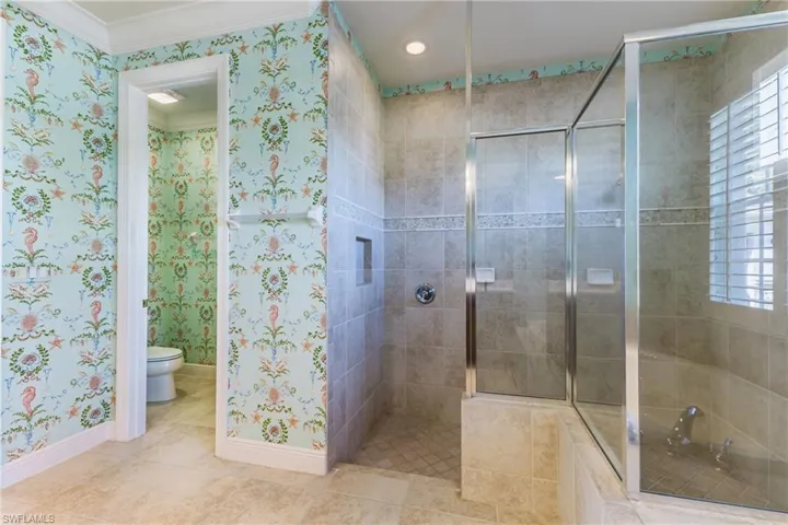 Bathroom featuring a shower stall, tile patterned flooring, wallpapered walls, and crown molding