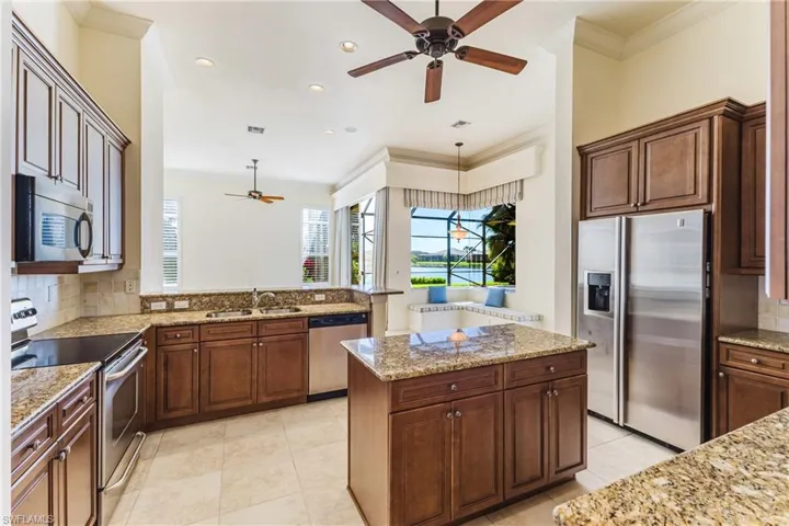 Kitchen with decorative backsplash, ornamental molding, appliances with stainless steel finishes, a peninsula, and light stone counters