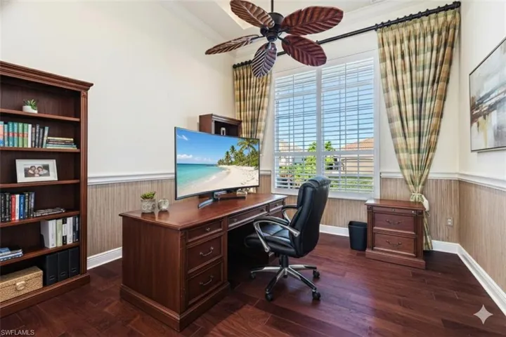 Home office with a wainscoted wall, crown molding, dark wood-style floors, and a ceiling fan