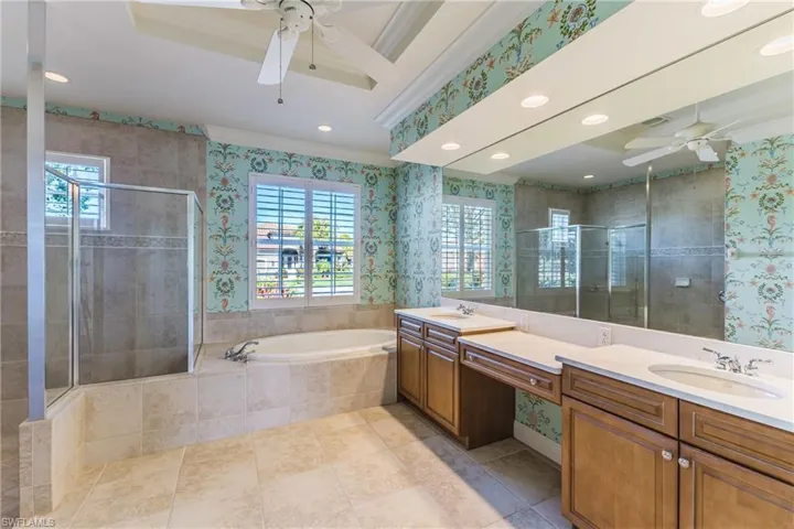 Bathroom featuring plenty of natural light, wallpapered walls, a ceiling fan, a stall shower, and ornamental molding