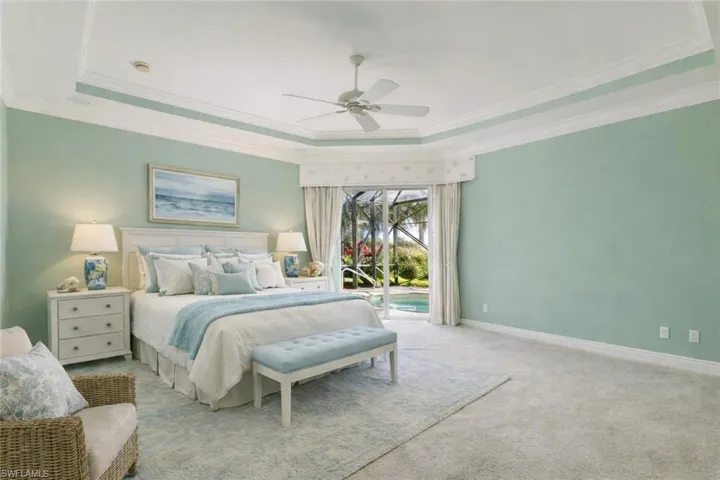 Primary Bedroom staged with a raised ceiling, access to exterior, carpet, crown molding, and ceiling fan