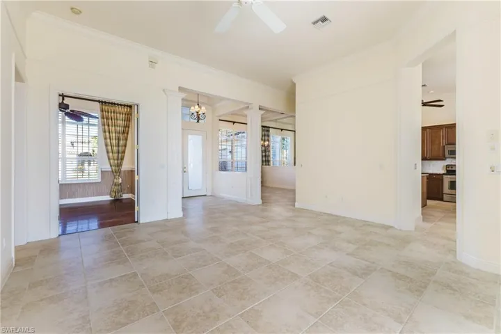 Living room with ceiling fan, ornamental molding, light tile patterned floors, and a chandelier