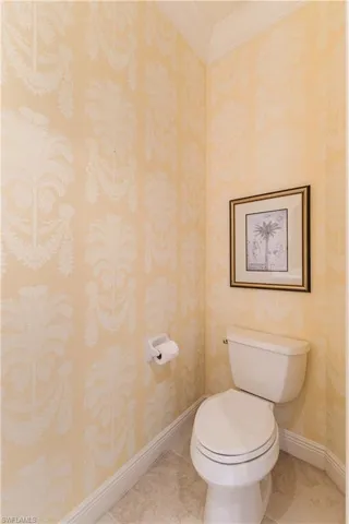 Bathroom featuring tile patterned floors, ornamental molding, and wallpapered walls