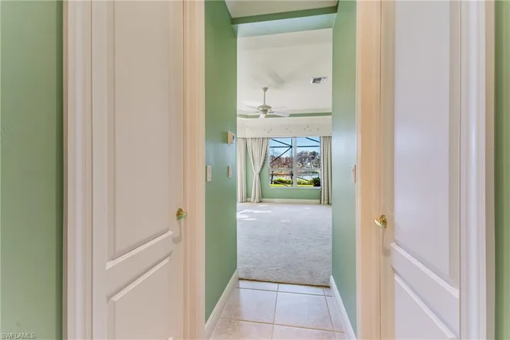 Corridor featuring light colored carpet, light tile patterned flooring, and crown molding