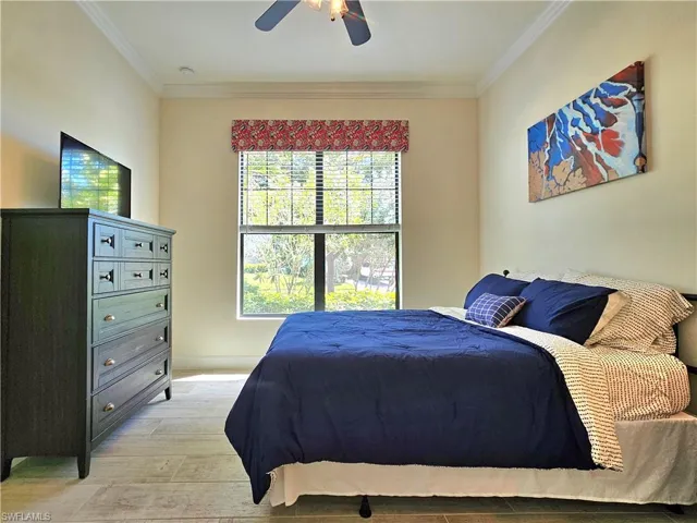 Bedroom featuring light wood-style floors, crown molding, and a ceiling fan