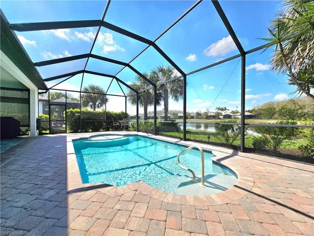 Outdoor pool featuring a patio, a water view, and glass enclosure