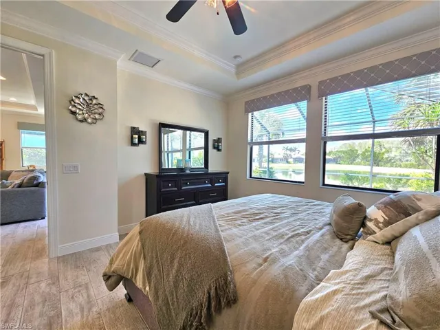 Bedroom with a tray ceiling, visible vents, light tile flooring, ornamental molding, and baseboards