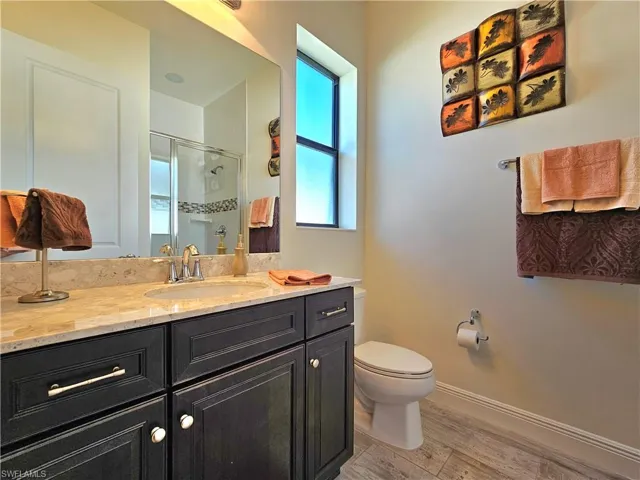 Full bathroom featuring toilet, a shower stall, baseboards, and vanity