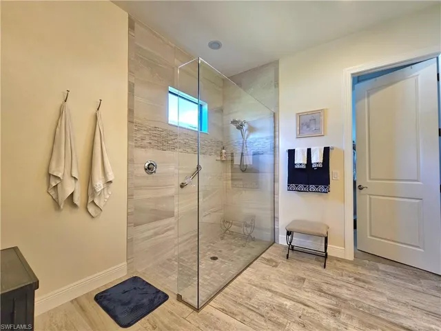 Full bath featuring a walk in shower, tile floors, and baseboards