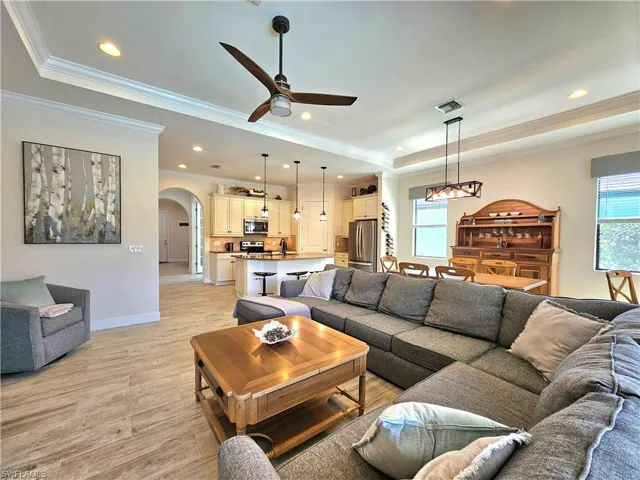 Living room featuring visible vents, arched walkways, baseboards, a raised ceiling, and light tile flooring