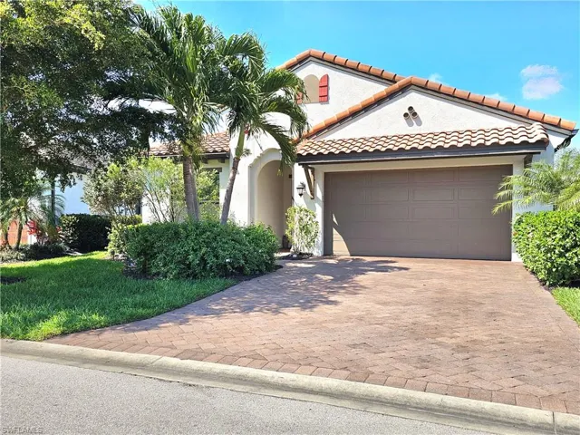 Mediterranean / spanish-style house with a garage, a front lawn, decorative driveway, and stucco siding