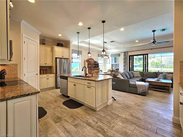 Kitchen with open floor plan, stainless steel appliances, crown molding, light tile floors, and a sink