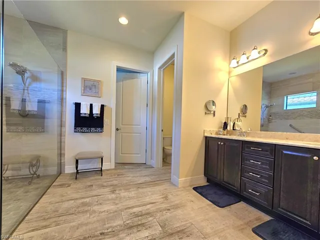 Bathroom featuring toilet, vanity, tile floors, baseboards, and a walk in shower