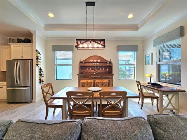 Dining area featuring baseboards, light wood-style flooring, a tray ceiling, and crown molding