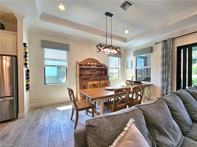 Dining room with light tile flooring, baseboards, visible vents, and a raised ceiling