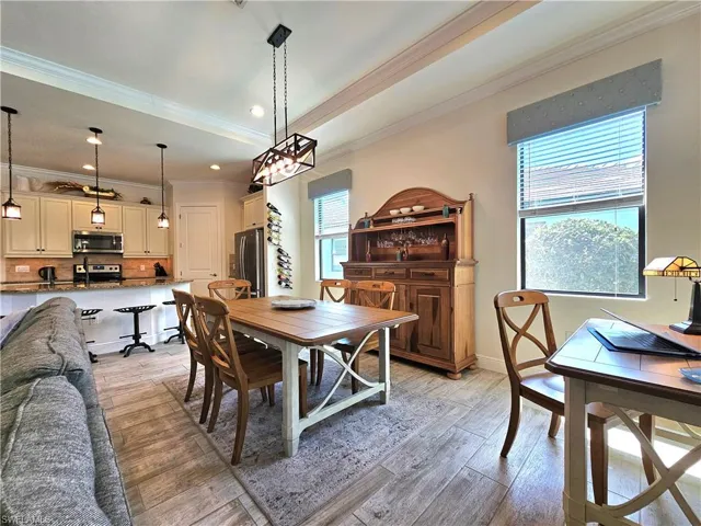 Dining space featuring baseboards, a raised ceiling, crown molding, light tile flooring, and recessed lighting