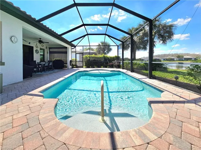 Outdoor pool featuring ceiling fan, a patio, a water view, and a lanai
