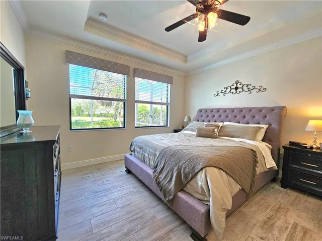 Bedroom featuring ornamental molding, a tray ceiling, and light tile floors