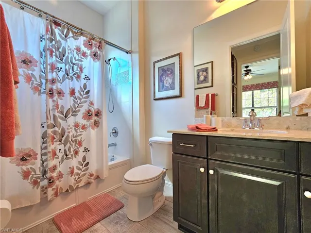 Full bath featuring wood like tile finished floors, shower / tub combo, vanity, and toilet