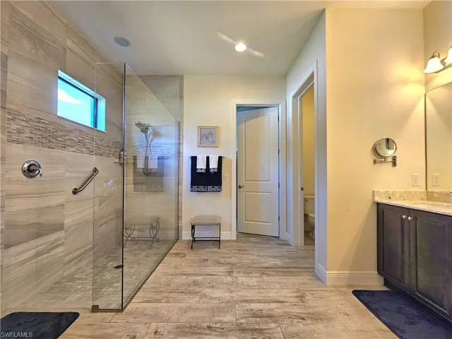 Full bathroom with a walk in shower, tile floors, toilet, and baseboards