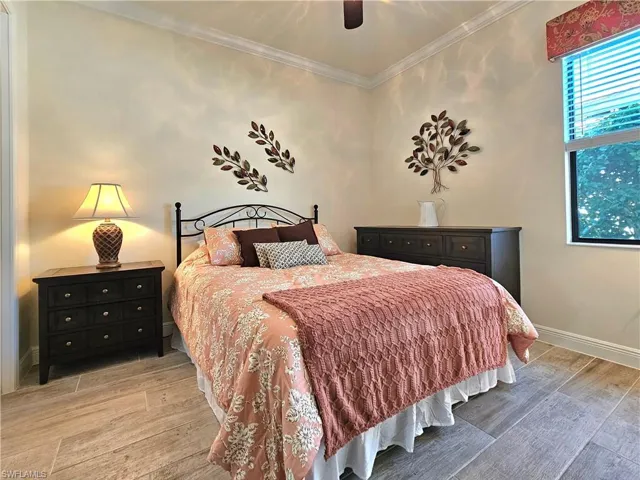 Bedroom featuring baseboards, ornamental molding, a ceiling fan, and light  tile floors