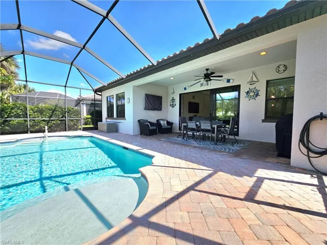Outdoor pool featuring ceiling fan, glass enclosure, outdoor dining space, and a patio area