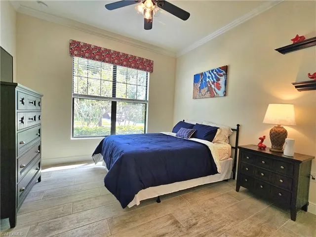 Bedroom with light wood-type flooring, ornamental molding, and a ceiling fan