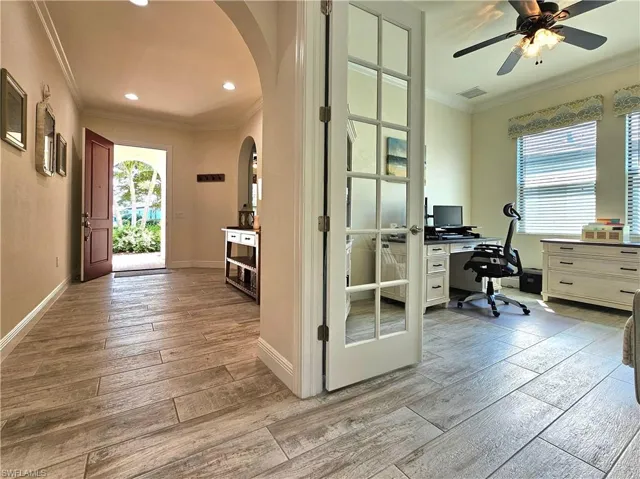 Home office with arched walkways, visible vents, baseboards, light tile floors, and crown molding