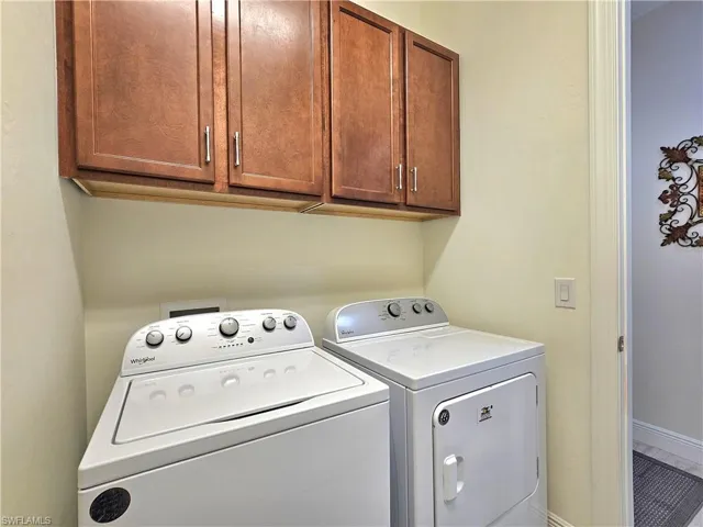 Laundry area with cabinet space, baseboards, and washer and clothes dryer