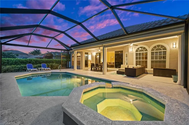 Pool at dusk featuring a patio area, an in ground hot tub, an outdoor hangout area, and a lanai