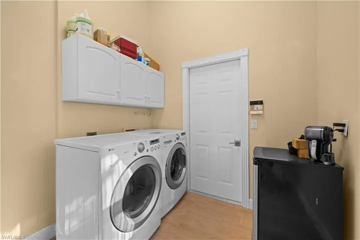 Laundry room with light hardwood / wood-style floors, washing machine and dryer, and cabinets