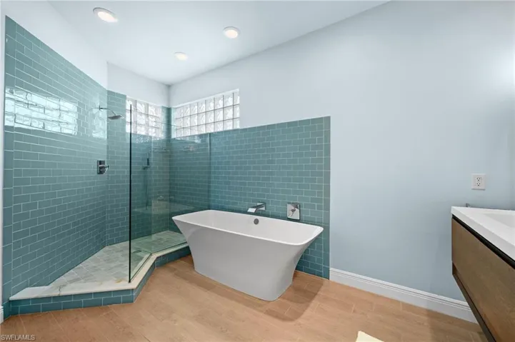 Bathroom with vanity, separate shower and tub, and hardwood / wood-style flooring