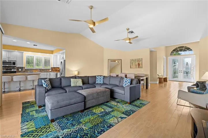 Living room with vaulted ceiling, french doors, light hardwood / wood-style flooring, and ceiling fan