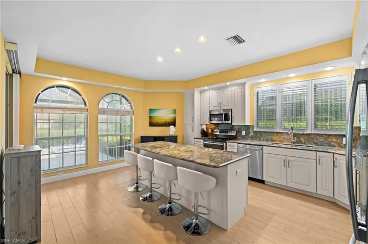 Kitchen with white cabinetry, tasteful backsplash, a center island, stainless steel appliances, and sink