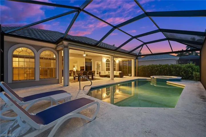 Pool at dusk featuring an in ground hot tub, a patio, ceiling fan, and a lanai