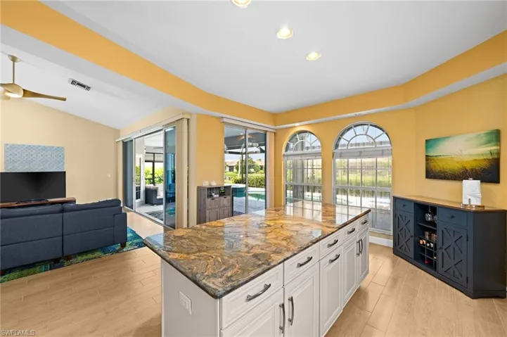Kitchen with a kitchen island, white cabinetry, lofted ceiling, and a healthy amount of sunlight