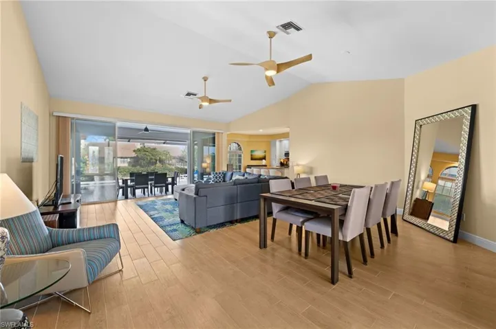 Living room with hardwood / wood-style flooring, ceiling fan, and vaulted ceiling