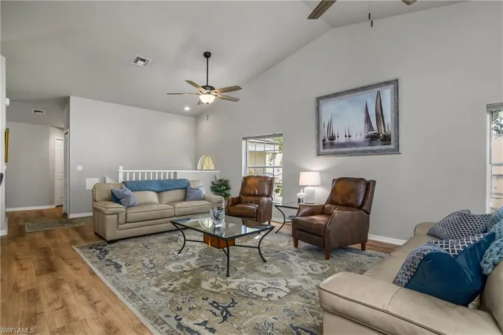Living room with wood finished floors, ceiling fan, and high vaulted ceiling