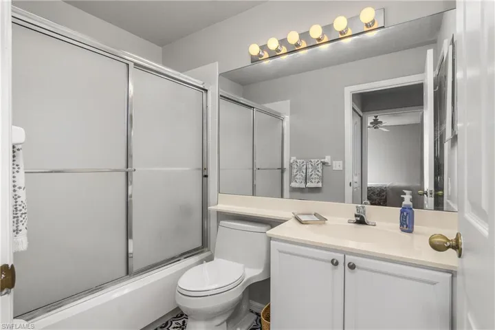 Full bath featuring bath / shower combo with glass door, vanity, and ceiling fan