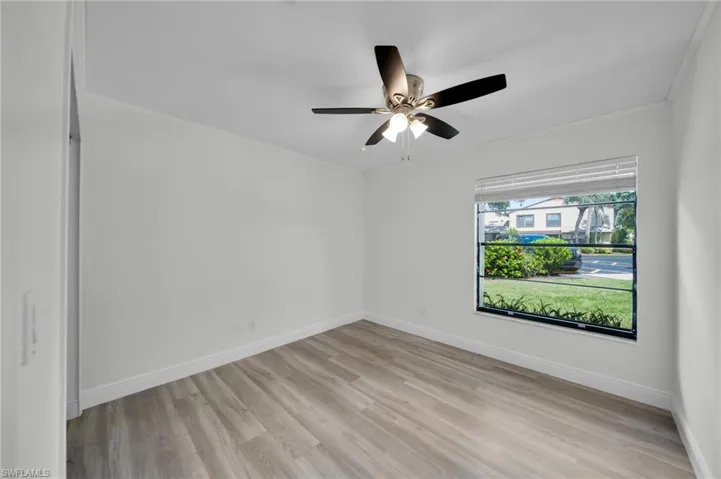 Spare room featuring light wood-type flooring, crown molding, and a ceiling fan