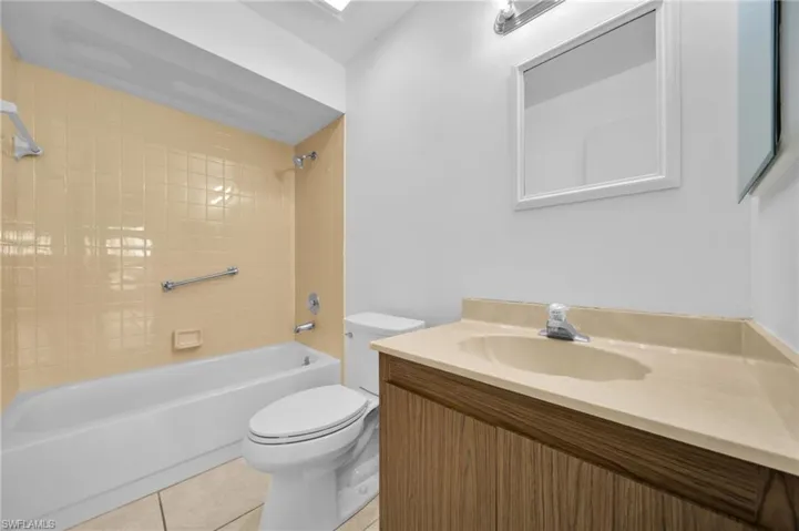 Bathroom featuring shower / bath combination, light tile patterned floors, and vanity