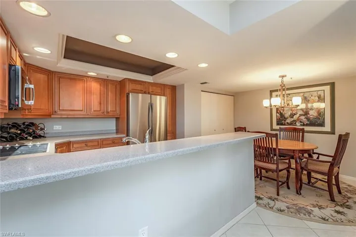 Kitchen featuring a tray ceiling, recessed lighting, light tile patterned floors, stainless steel appliances, and a peninsula