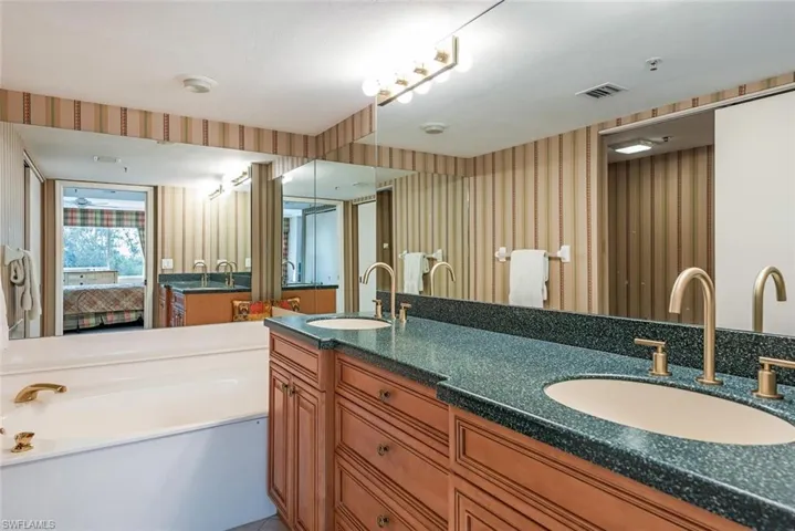 Ensuite bathroom with double vanity, wallpapered walls, stall shower and a bath