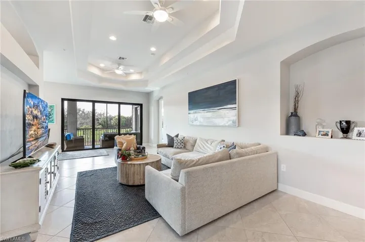 Living area with light tile patterned floors, a ceiling fan, recessed lighting, and a tray ceiling
