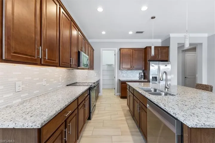 Kitchen featuring appliances with stainless steel finishes, a sink, ornamental molding, tasteful backsplash, and recessed lighting